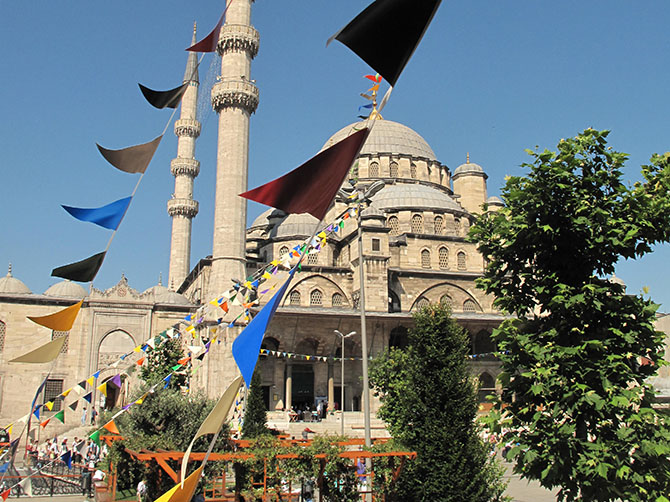 Une mosquée, des drapeaux, le ciel bleu.